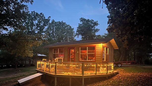 A wooden cabin with a deck, surrounded by trees. - Antler Ridge Cabin One (Murfreesboro)