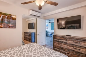 A bedroom with a bed, a ceiling fan, a mounted TV, and a wardrobe.