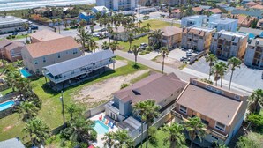 Zona residencial costera con edificios de varios pisos, una piscina visible y una playa al fondo.