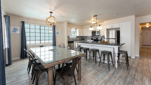 Una cocina moderna con una isla central, sillas de madera oscura y una mesa de comedor de vidrio.