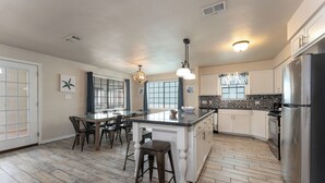 Una cocina moderna con una isla central, armarios blancos y un refrigerador de acero inoxidable.