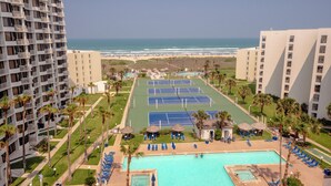 Ein Hotel mit Poolbereich, Tennisplätzen und Blick auf den Strand.