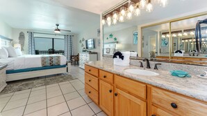 A modern bathroom with a large mirror, a sink, and a vanity with drawers.