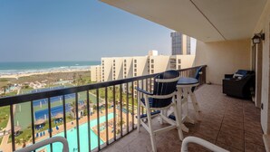 A balcony with a view of a beach and a tennis court.
