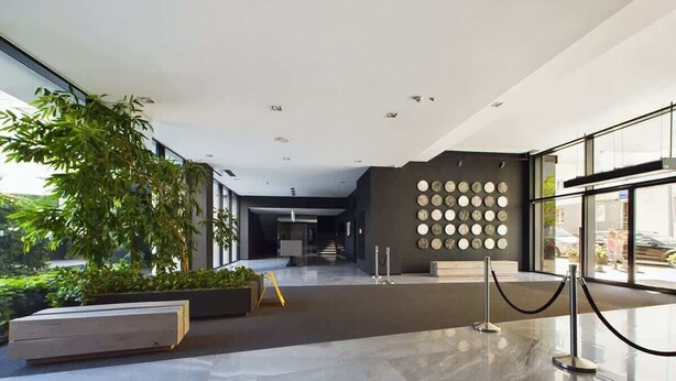 Un hall d’entrée moderne avec une entrée en verre, un escalier et un mur orné de motifs circulaires.