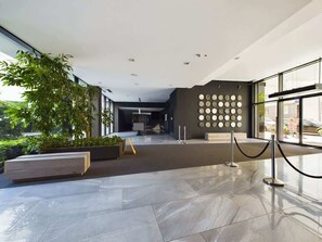 A modern lobby with a glass entrance, a staircase, and a wall with circular decorations.