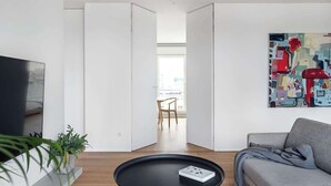 Un salon moderne avec une table basse noire, un canapé gris et un tableau abstrait aux couleurs vives accroché au mur.