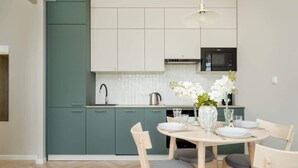 A modern kitchen with teal cabinets, a white countertop, and a dining area with a round table and chairs.