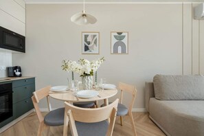 A modern kitchen with a microwave, coffee maker, and a dining table set for four. - Modern Apartment | Parking, Gym and Air Conditioning (Wrocław)
