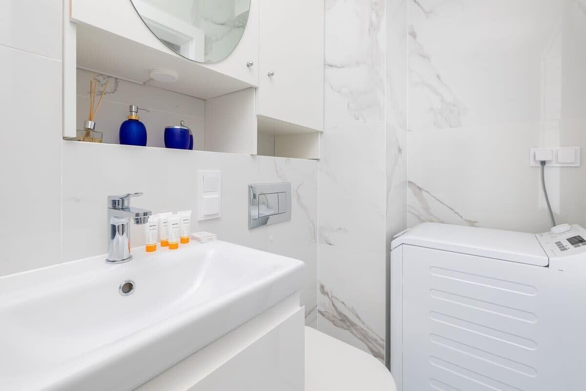 Une salle de bain moderne avec un lavabo blanc, un miroir et des murs en marbre.
