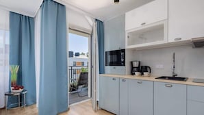 A modern kitchen with grey cabinets, a black coffee machine, and a window overlooking a balcony.