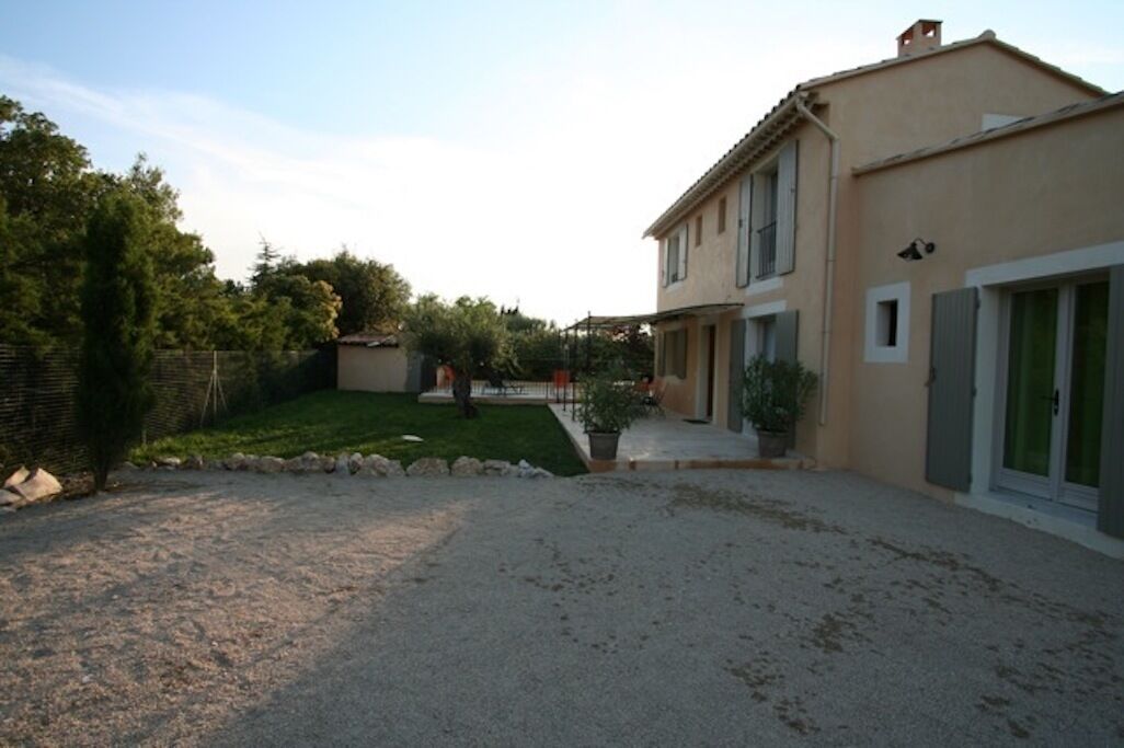 A two-story house with a gravel driveway, a small garden, and a wooden fence.