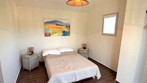 A bedroom with a bed, two bedside tables, a painting on the wall, a window, and a hanging light fixture. - Family-friendly, Cozy and Peaceful Villa with Pool in Apt en Luberon, Provence (Apt)