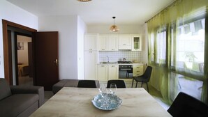 A modern kitchen with white cabinets, a dining area with a table, and a sofa. - A Casa di Doralucia - Santa Maria di Leuca (Santa Maria di Leuca)