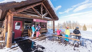 Une cabane en bois avec une pancarte indiquant « Cabane à bonbons » et un banc à l’extérieur.