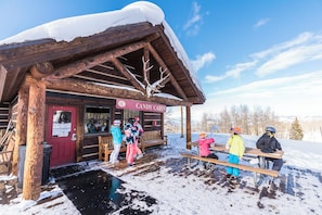 Una casetta di legno con un cartello che riporta 'Candy Cabin' e una panchina all'esterno.