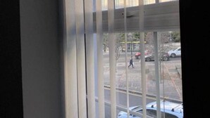 A view through window blinds of a building with multiple windows and a parking lot with cars. - Brownlows Inn Rooms  (Liverpool)