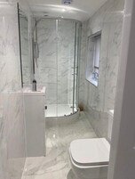 Un baño moderno con ducha de vidrio, inodoro y tocador con espejo.