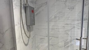 A modern bathroom with a glass shower enclosure, marble walls, and a control panel. - Brownlows Inn Rooms  (Liverpool)