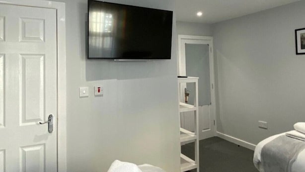 A hotel room with a bed, a TV mounted on the wall, a white wardrobe, and a door. - Brownlows Inn Rooms  (Liverpool)