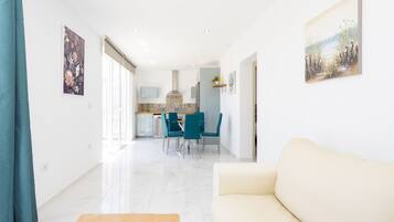Una sala de estar moderna con un sofá, una mesa de centro de madera y una zona de comedor con sillas y una mesa.