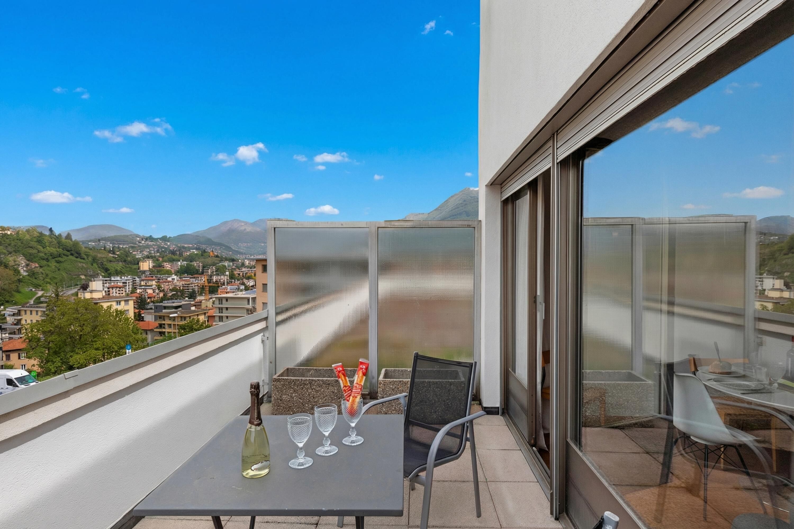 Un balcon avec une table mise pour deux, une bouteille et deux verres.