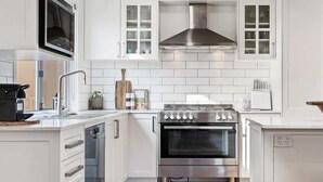 A modern kitchen with white cabinetry, a stainless steel range hood, and a built-in oven. - Stunning Family Home on Prince - Close to CBD! (Orange)