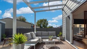 A covered outdoor patio with a sofa, coffee table, and potted plants. - Stunning Family Home on Prince - Close to CBD! (Orange)