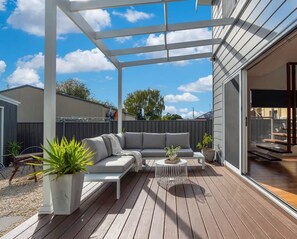 A covered outdoor patio with a sofa, coffee table, and potted plants. - Stunning Family Home on Prince - Close to CBD! (Orange)