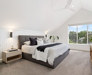 A bedroom with a bed, bedside table, and a large window with a view. - Stunning Family Home on Prince - Close to CBD! (Orange)