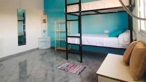 A room with bunk beds, a desk, a chair, a lamp, and a window.