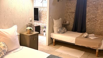 Habitación de hotel con dos camas, un escritorio pequeño, un televisor montado en la pared y un cuadro decorativo.