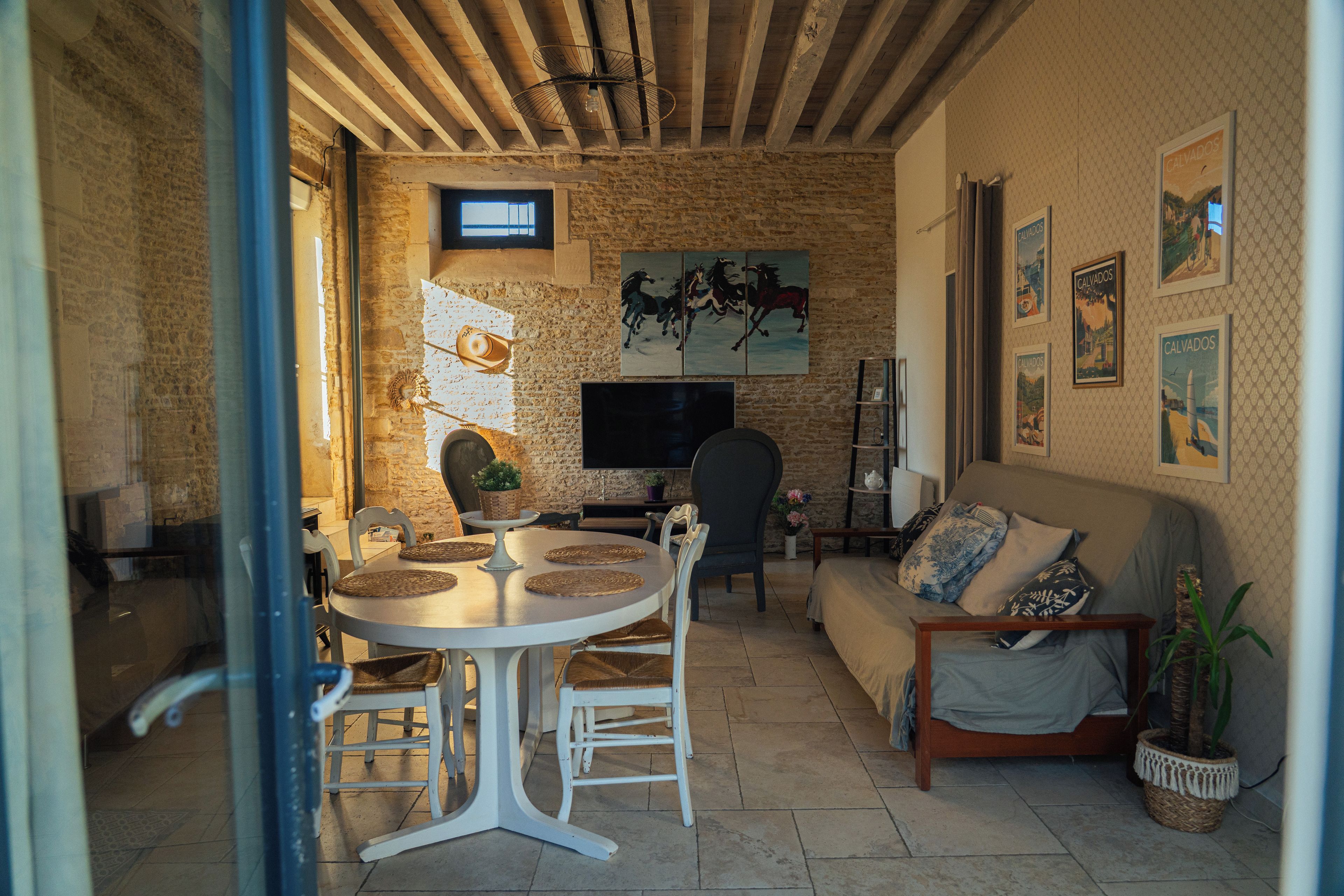 Un salon chaleureux avec un mur en pierre, une table à manger ronde et un canapé confortable.