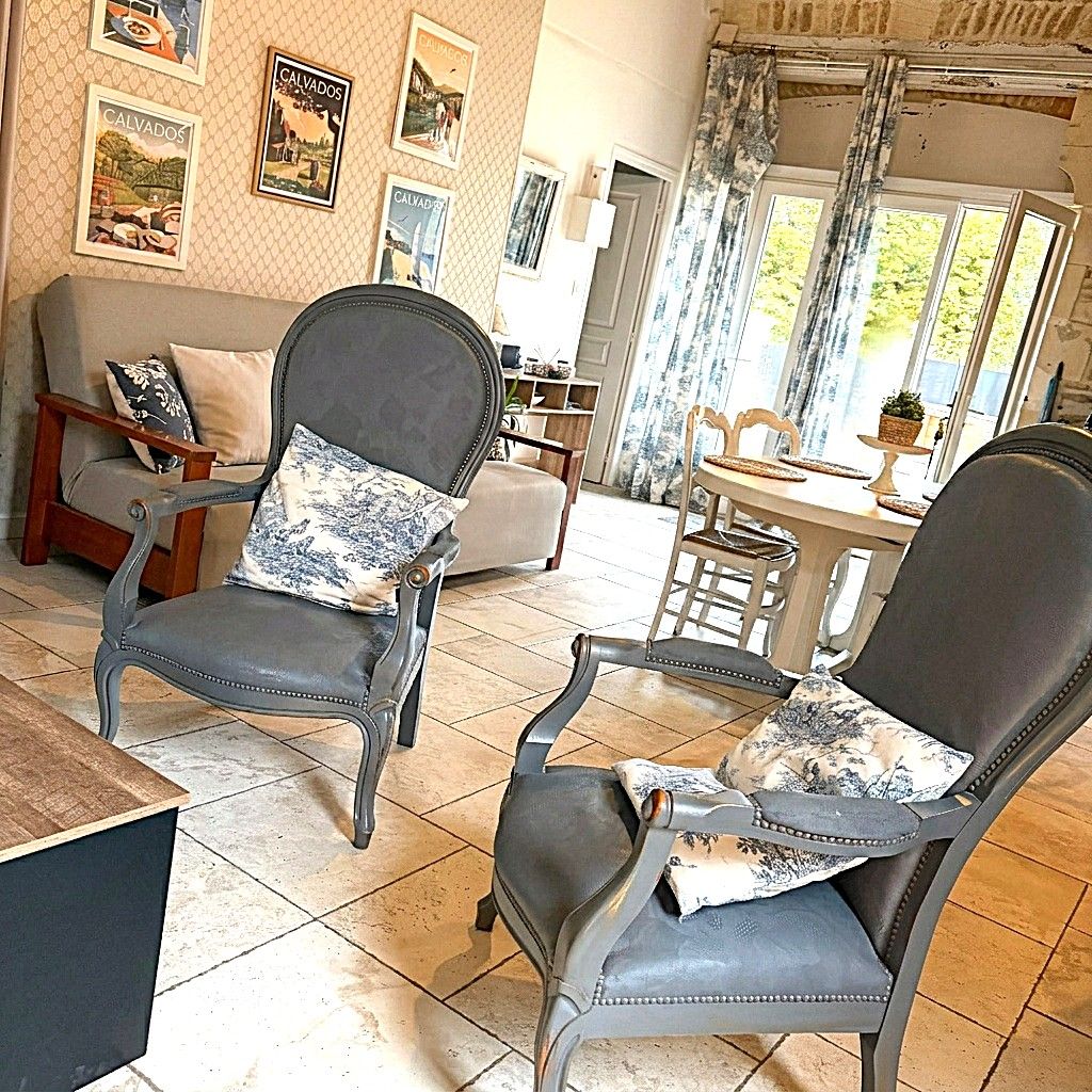 Ein Wohnzimmer mit einer Couch, zwei Sesseln, einem Couchtisch und einem Essbereich mit Tisch und Stühlen.