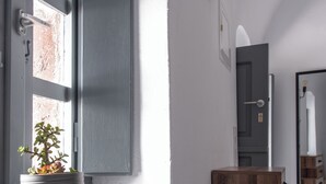 A modern interior with a wooden cabinet, a potted plant, and a wall-mounted light fixture. - Prive by Noelia Suites | Sunset View |Hot Tub-2Pax (Finikia)
