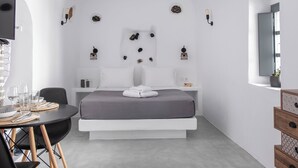 A modern, minimalist bedroom with a bed, bedside tables, a desk, and chairs. - Prive by Noelia Suites | Sunset View |Hot Tub-2Pax (Finikia)
