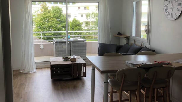 A modern living room with a dining area, large windows, and a view of the outside. - Joli Appartement T2 Vannes / 2 à 4 Personnes (Vannes)