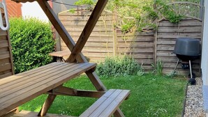 En træterrasse med et picnicbord og grillområde.