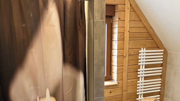 Et badeværelse med træloft, hvid radiator og toilet.