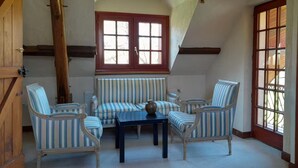 A room with a sloped ceiling, a wooden door, a window with a view, striped upholstered furniture, and a table.