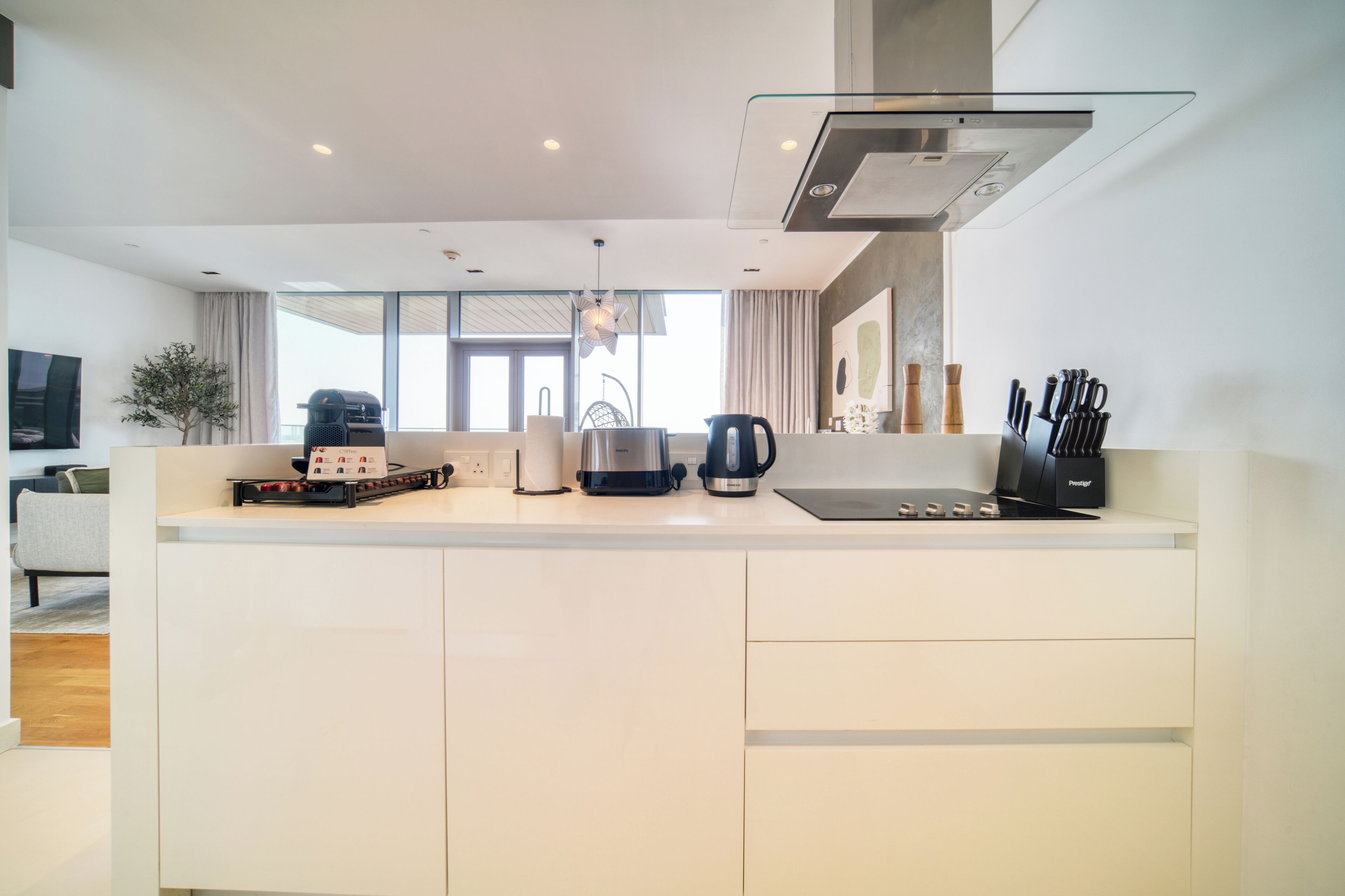 A modern kitchen with a large island, a coffee maker, and a kettle.