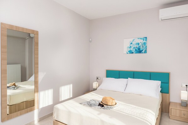 Ein Schlafzimmer mit einem Bett, einem Nachttisch, einem Spiegel und einer Wand-Klimaanlage.