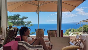 A woman relaxing on a wicker chair with a view of the ocean.