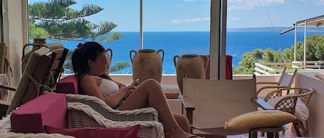 A woman relaxing on a wicker chair with a view of the ocean.
