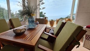 A wooden table with chairs, a vase with yellow flowers, and a bowl of snacks.
