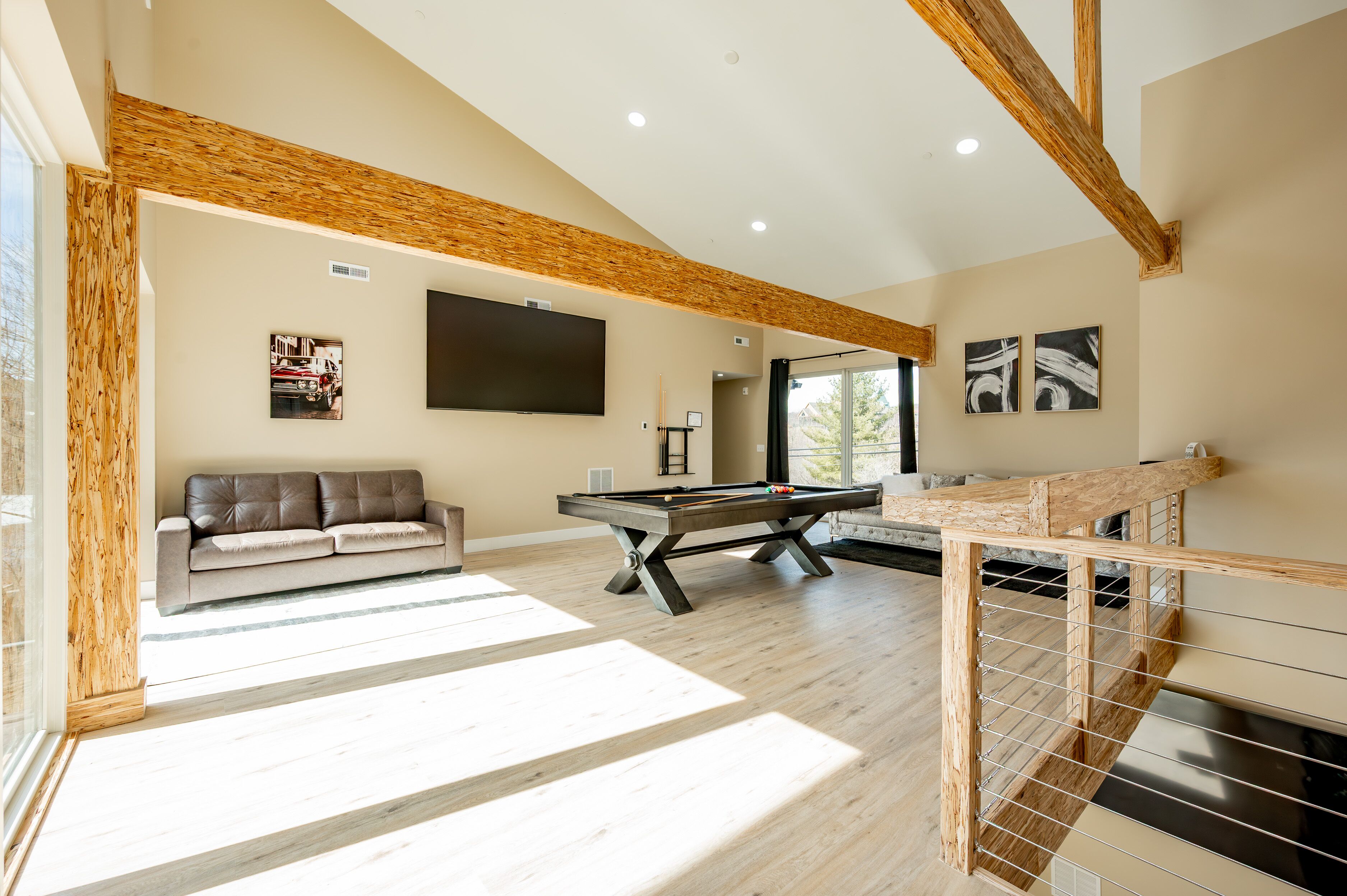 Amplia sala de estar con mesa de billar, sofá y escalera con barandilla de madera.