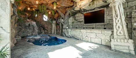 A spa area with a hot tub, stone walls, and hanging plants.