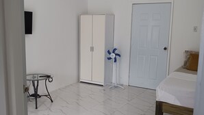 A room with a bed, a wardrobe, a table, and a fan. - Self Contained Room 3 Tower Isles near Ocho Rios  (Tower Isle)