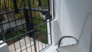 A balcony with a metal gate, a chair, and a view of greenery. - Self Contained Room 3 Tower Isles near Ocho Rios  (Tower Isle)