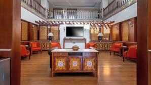 A spacious lobby with a central island, wooden furniture, and a staircase with ornate railings.